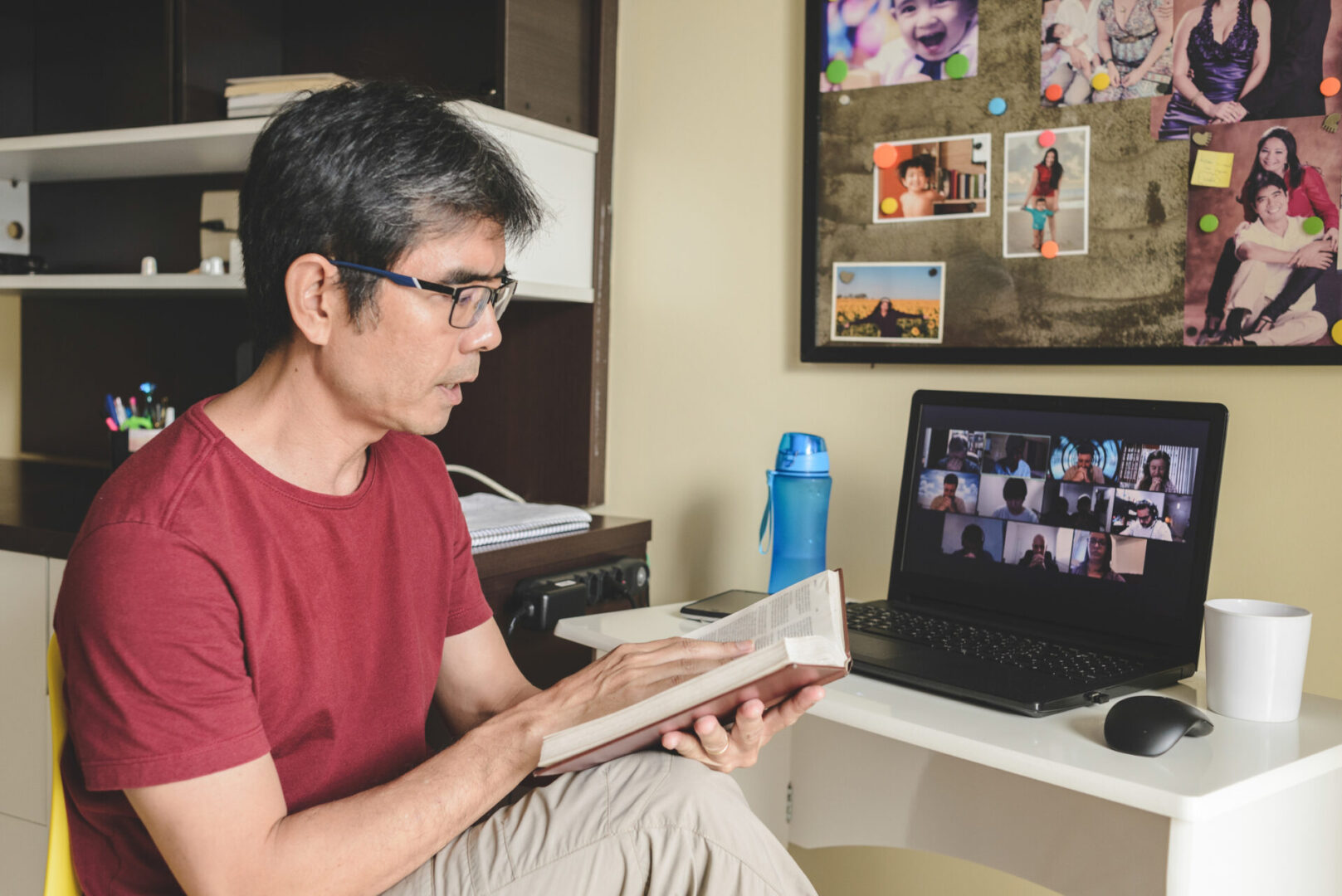 Man reading book during video call meeting.