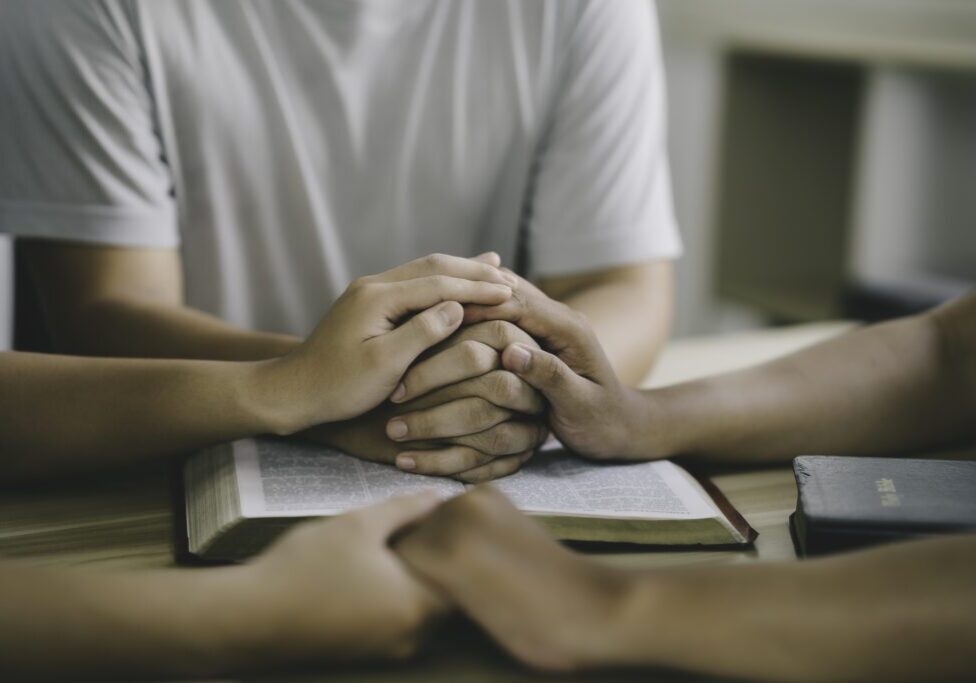 People holding hands over an open book.